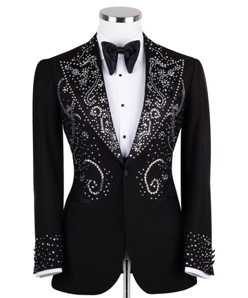 Black embellished three-piece tuxedo with intricate crystal and bead patterns on satin peak lapels, chest, and cuffs. Features a matching vest. Handcrafted luxury suit from Charly Luxury Istanbul.