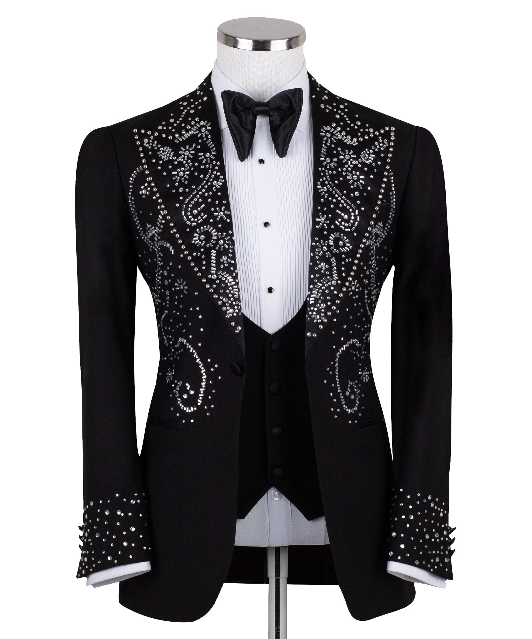 Black embellished three-piece tuxedo with intricate crystal and bead patterns on satin peak lapels, chest, and cuffs. Features a matching vest. Handcrafted luxury suit from Charly Luxury Istanbul.