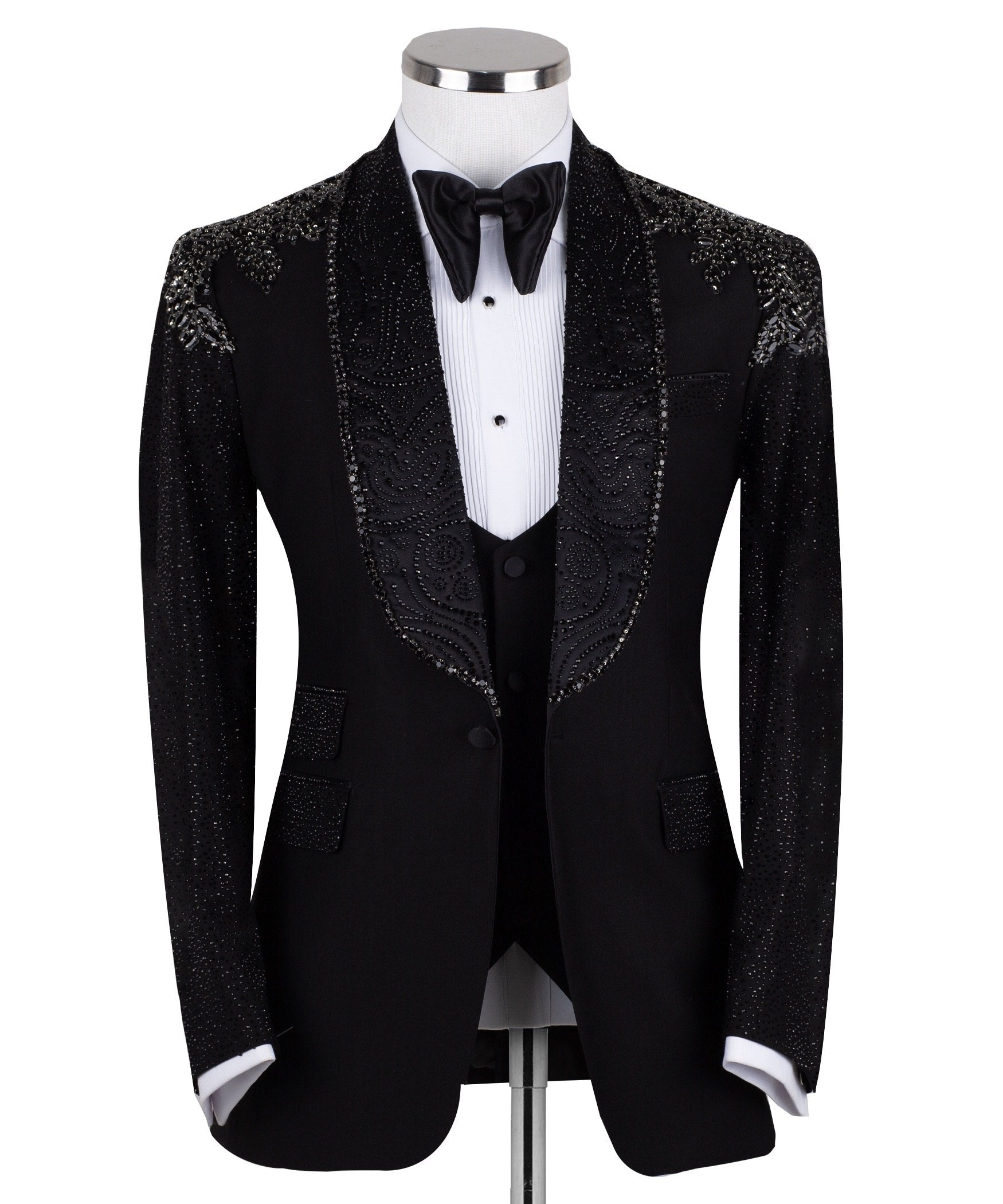 Black three-piece tuxedo on a mannequin, featuring a heavily hand-embellished shawl lapel, shoulders, and sleeves with intricate sparkling beadwork. The tuxedo includes a matching black vest and trousers, designed in a slim fit style, showcasing luxurious craftsmanship from Istanbul.