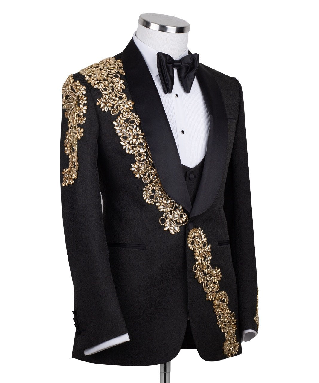 Front view of a black jacquard three-piece tuxedo with intricate gold hand-embellishments on the shawl lapel, shoulder, and cuffs, displayed on a mannequin. From Charly Luxury, handcrafted in Istanbul.