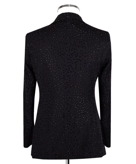 Close-up of a black double-breasted tuxedo jacket on a mannequin, showcasing intricate hand-embellishments with beads and crystals on the lapels and body. Features a peak lapel and black buttons, paired with a white shirt and black bow tie. Front view showing the full jacket and details.
