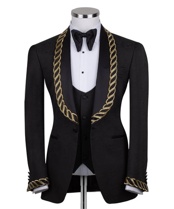 Front view of Charly Luxury's black jacquard three-piece tuxedo with opulent gold chain embellishments on the shawl lapel and cuffs, tailored in Istanbul. Includes jacket, vest, and trousers.