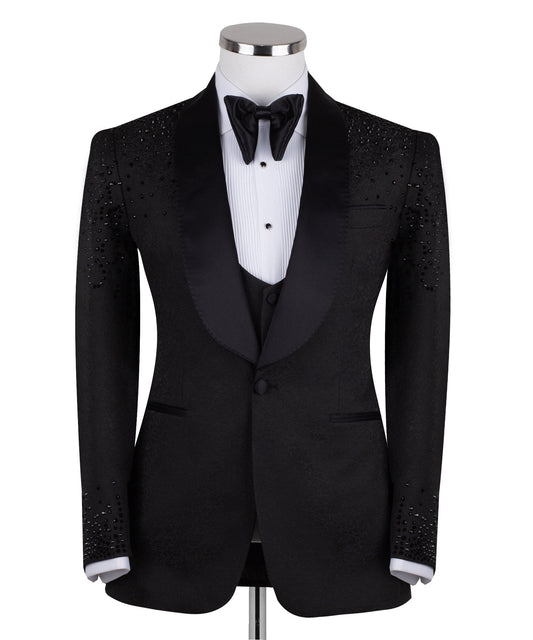 Black hand-embellished three-piece tuxedo by Charly Luxury, featuring an intricate beaded pattern on the shoulders and back, satin shawl lapel, and matching vest and trousers. Masterfully crafted in Istanbul for luxury events.