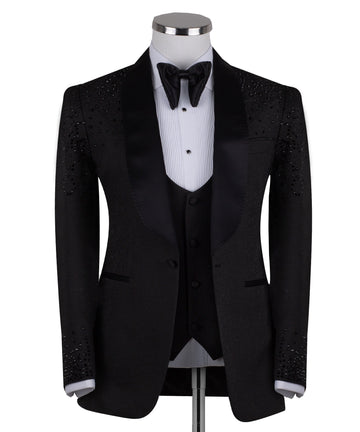 Black hand-embellished three-piece tuxedo by Charly Luxury, featuring an intricate beaded pattern on the shoulders and back, satin shawl lapel, and matching vest and trousers. Masterfully crafted in Istanbul for luxury events.