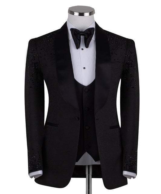 Black hand-embellished three-piece tuxedo by Charly Luxury, featuring an intricate beaded pattern on the shoulders and back, satin shawl lapel, and matching vest and trousers. Masterfully crafted in Istanbul for luxury events.