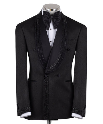 Front view of a black textured double-breasted tuxedo with hand-embellished shawl lapels, cuffs, and front trim. The trousers have a satin side stripe. High-end luxury formal wear from Charly Luxury.