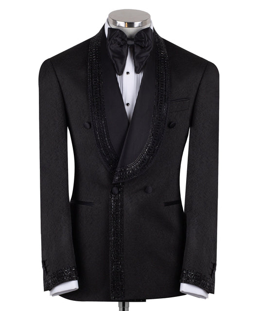 Front view of a black textured double-breasted tuxedo with hand-embellished shawl lapels, cuffs, and front trim. The trousers have a satin side stripe. High-end luxury formal wear from Charly Luxury.