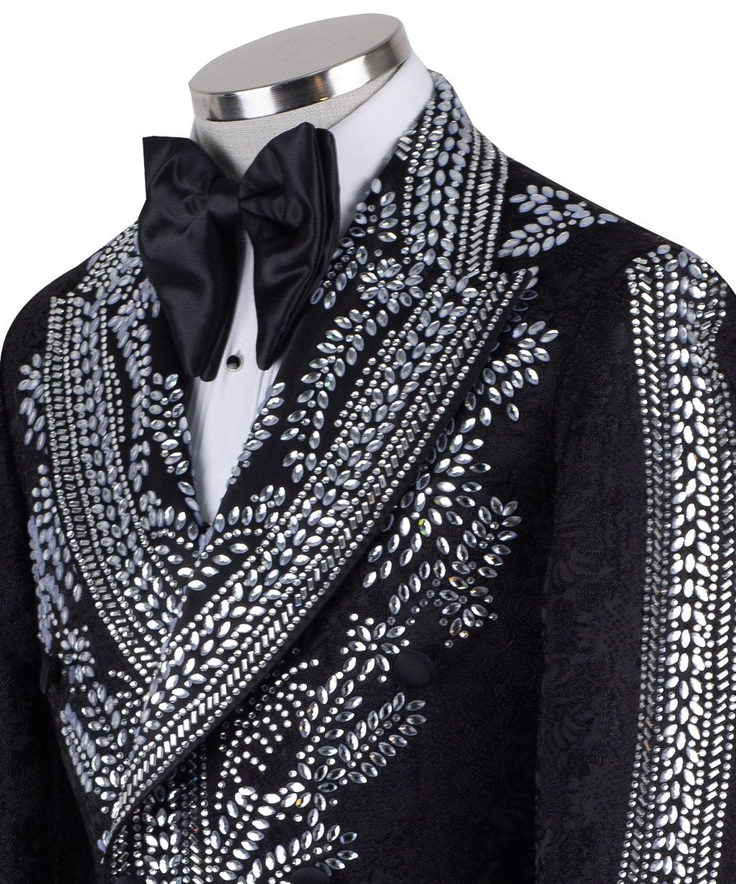 Front view of a black double-breasted tuxedo jacket with extensive silver embellishments, featuring a peak lapel and slim fit design on a mannequin. Back view and close-up showing intricate hand-beading detail.