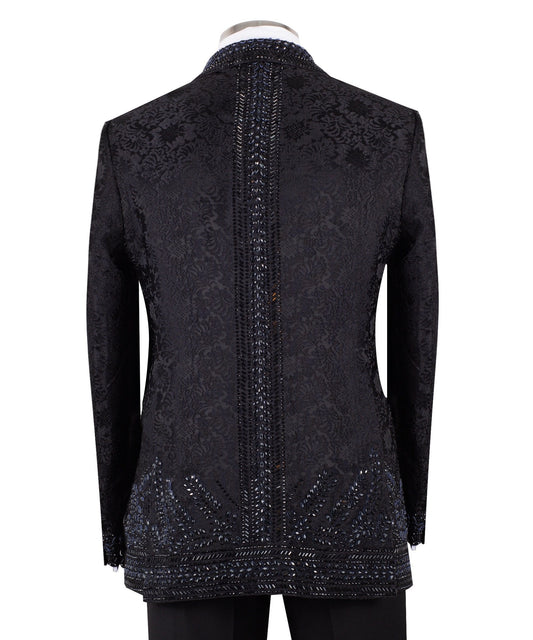 Front view of a luxurious black embellished jacquard double-breasted tuxedo jacket with intricate sequin and bead work on lapels, body, and sleeves, paired with black trousers, worn on a mannequin. From Charly Luxury, handcrafted in Istanbul.