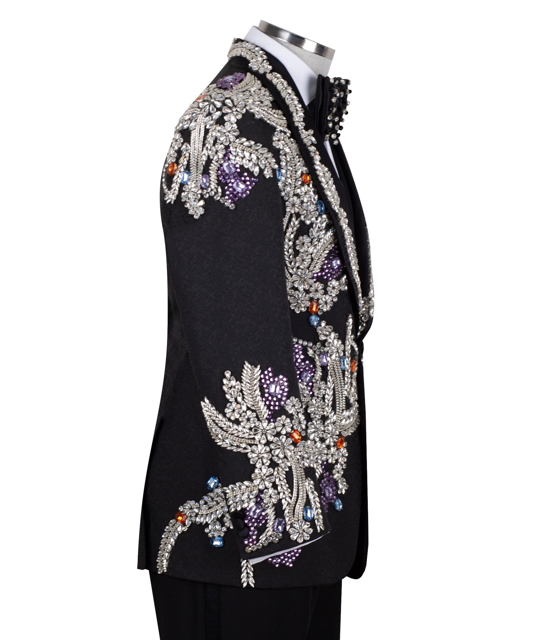 Front and side view of a black tuxedo jacket with extensive silver, purple, orange, and blue crystal and gemstone embellishments in floral and baroque patterns, paired with matching black trousers and vest, on a mannequin. Showcases intricate hand-embellished details and luxurious craftsmanship from Charly Luxury, Istanbul.