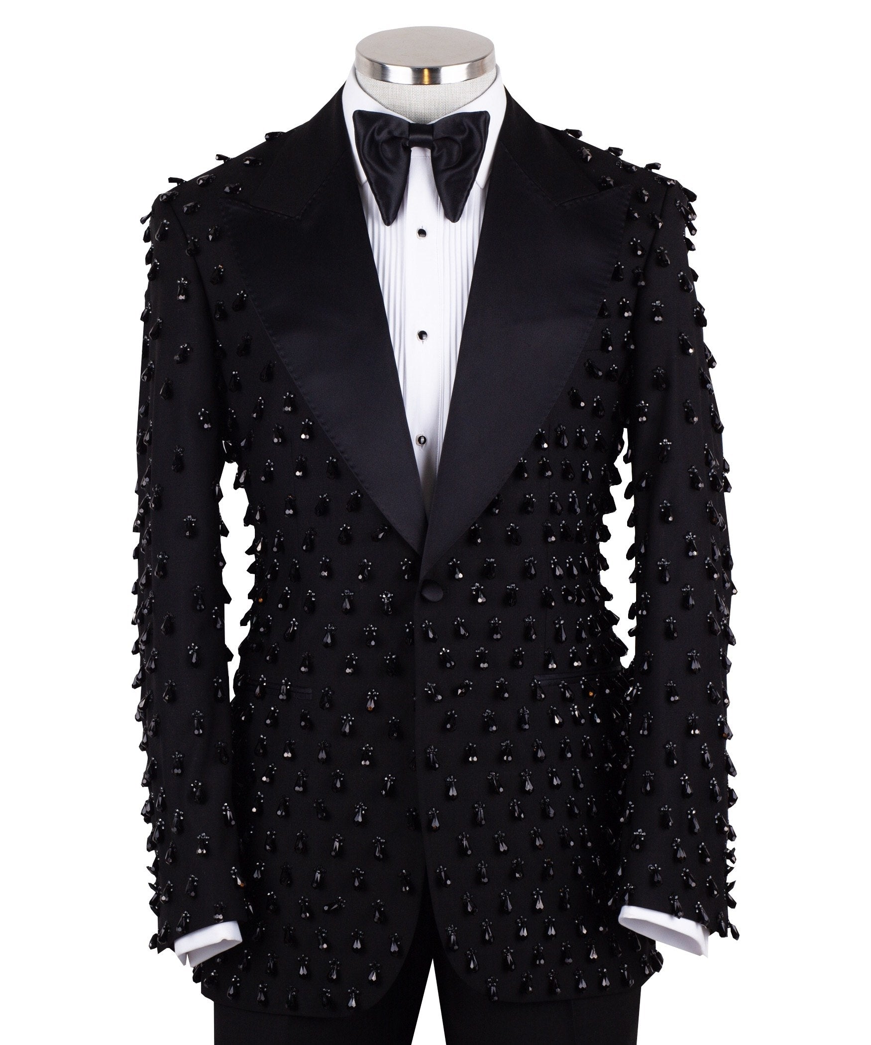 Front view of a black hand-embellished luxury tuxedo jacket with satin peak lapels and matching trousers on a mannequin. Side view close-up of the jacket's intricate black bead embellishments. Close-up of the tuxedo trousers with a satin side stripe and high-waisted detail.