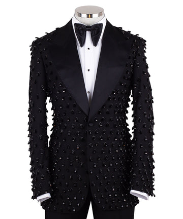Front view of a black hand-embellished luxury tuxedo jacket with satin peak lapels and matching trousers on a mannequin. Side view close-up of the jacket's intricate black bead embellishments. Close-up of the tuxedo trousers with a satin side stripe and high-waisted detail.