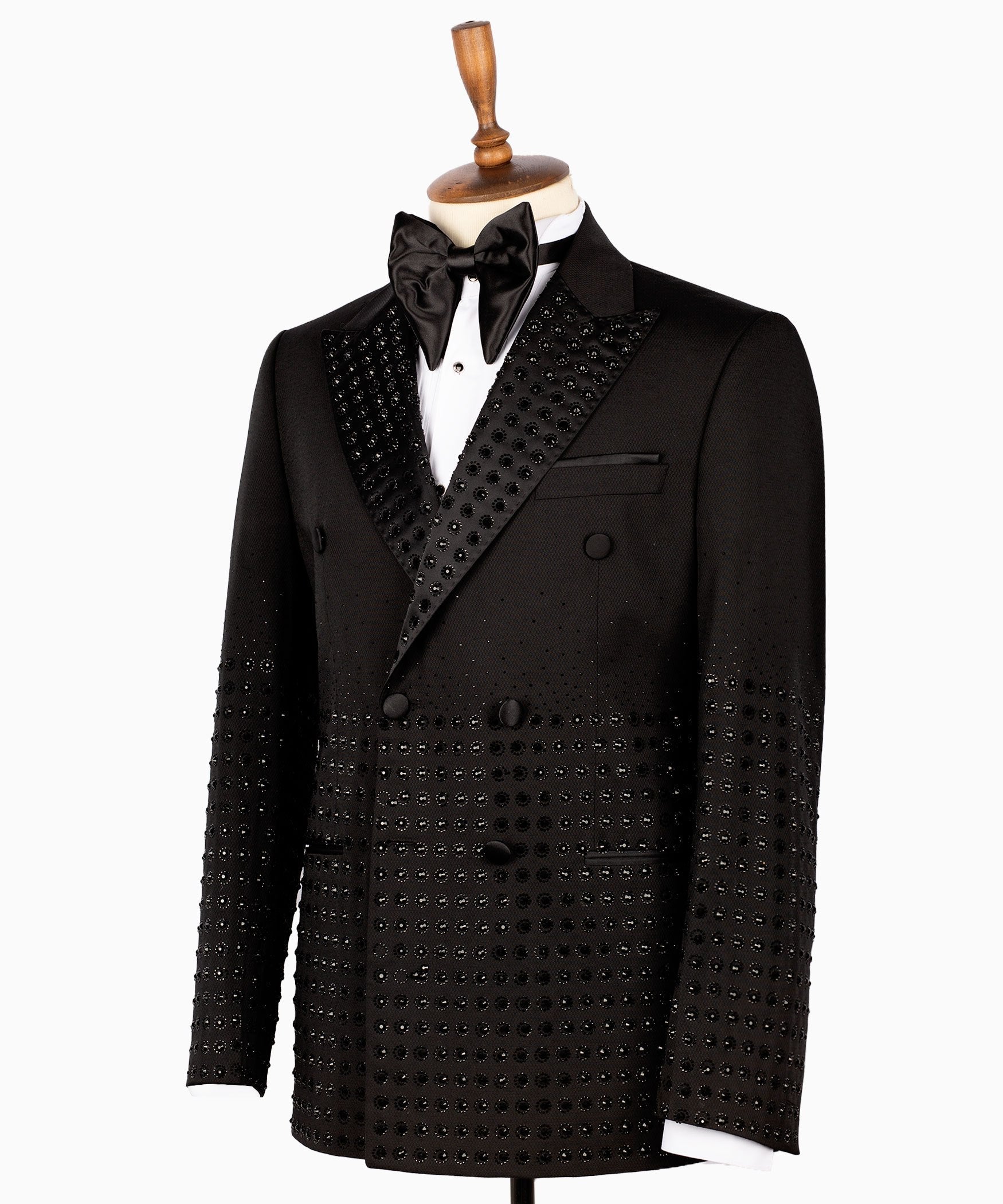 Front view of a black double-breasted tuxedo jacket featuring intricate hand-embellished studs on the peak lapels, shoulders, sleeves, and lower body, styled with matching black trousers with a satin side stripe. Handcrafted luxury from Charly Luxury Istanbul.