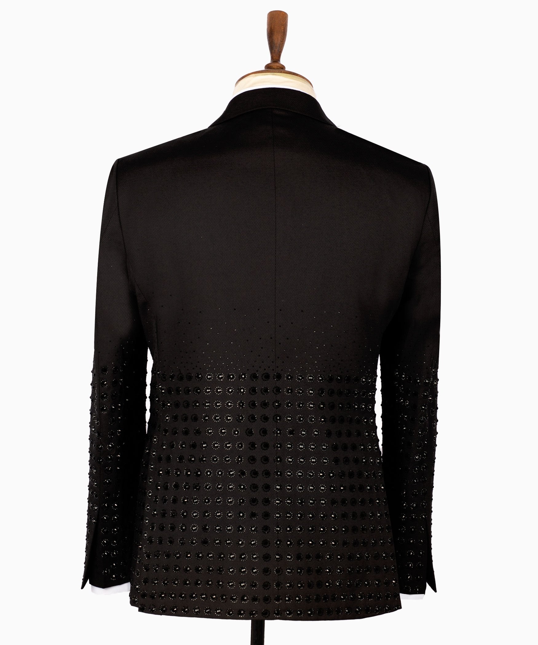 Front view of a black double-breasted tuxedo jacket featuring intricate hand-embellished studs on the peak lapels, shoulders, sleeves, and lower body, styled with matching black trousers with a satin side stripe. Handcrafted luxury from Charly Luxury Istanbul.