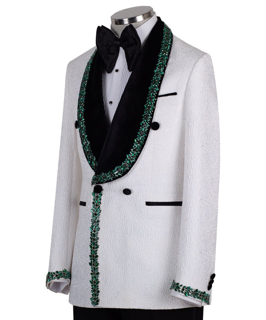 White double-breasted tuxedo jacket with textured fabric, black velvet shawl lapel, emerald green hand-embellished jewels, black buttons, and matching black trousers. Luxurious, handcrafted in Istanbul by Charly Luxury.