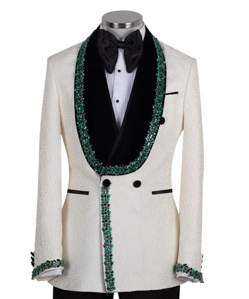 Charly Luxury Cream textured double-breasted tuxedo with black velvet shawl lapel and emerald green hand-embellishments on jacket front, lapel, and cuffs, paired with black trousers.