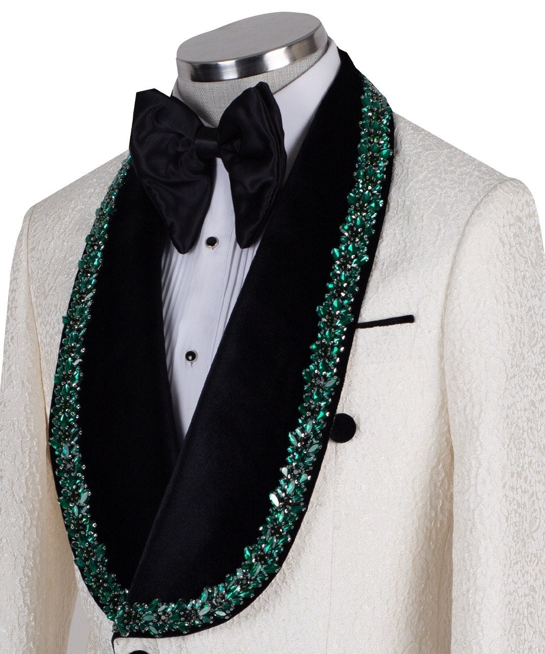 Charly Luxury Cream textured double-breasted tuxedo with black velvet shawl lapel and emerald green hand-embellishments on jacket front, lapel, and cuffs, paired with black trousers.