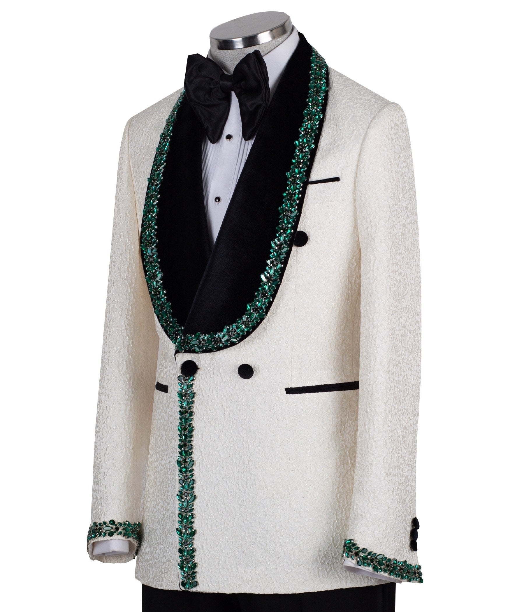 Charly Luxury Cream textured double-breasted tuxedo with black velvet shawl lapel and emerald green hand-embellishments on jacket front, lapel, and cuffs, paired with black trousers.