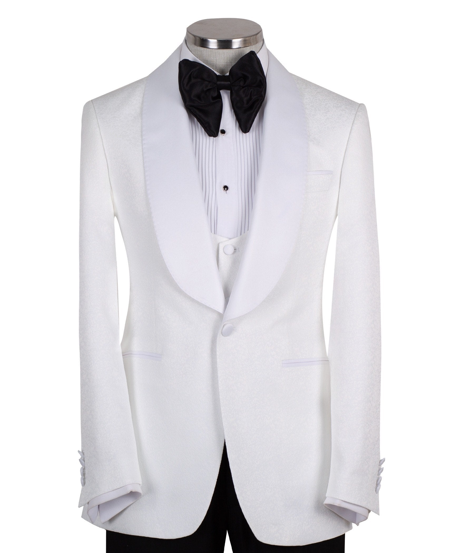 Front view of a white jacquard patterned single-breasted tuxedo jacket with a white satin shawl lapel, displayed on a mannequin. Includes a matching white jacquard vest and black trousers. Handmade in Istanbul luxury bespoke menswear.