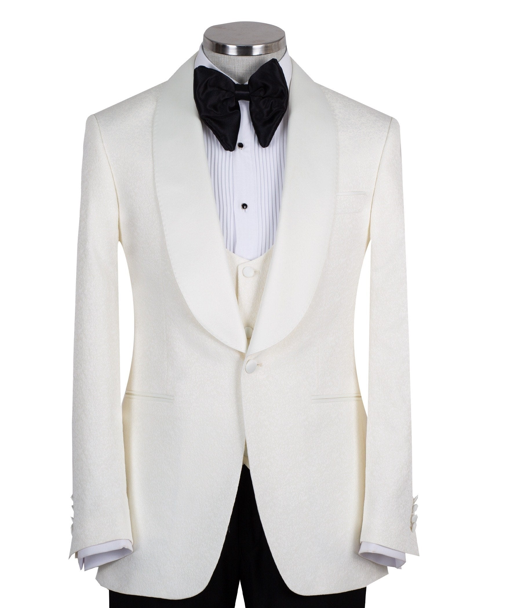 Front view of an ivory jacquard three-piece tuxedo with black trousers on a mannequin. Features a single-breasted jacket with a satin shawl lapel, matching U-neck vest, and subtle floral pattern. Ideal for weddings and formal events.